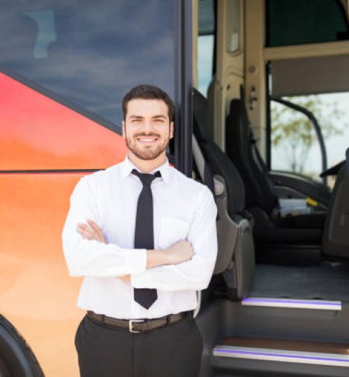 Portrait of good looking driver standing arms crossed outside intercity bus